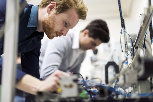 Two young handsome engineers working on electronics components Two young handsome engineers working on electronics components and fixing broken chips