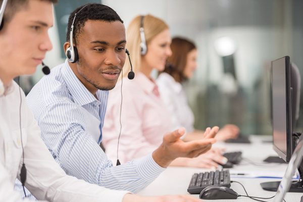 Call center Phone operator working at call centre office helping hiss colleague.